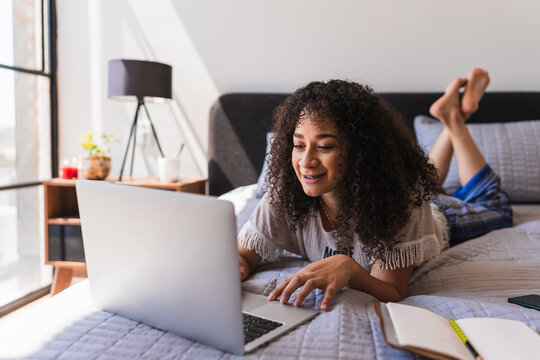 Smiling Woman Using A Computer On Her Bed