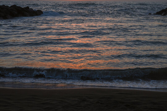 The blue sea glows orange at dusk