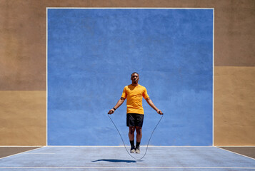 Fit black sprinter jumping in stadium on sunny day