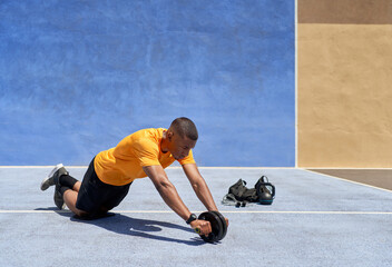 Young black sportsman using ab roller during workout