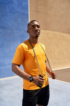 Young black sportsman standing on court in sunlight
