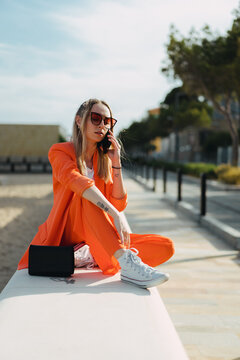 A woman sits near the beach for a call