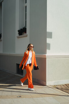 A woman in orange clothes walks fast in the city