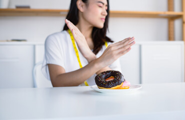 Asian women are reluctant to eat delicious donuts. Because her are aiming to lose weight.
