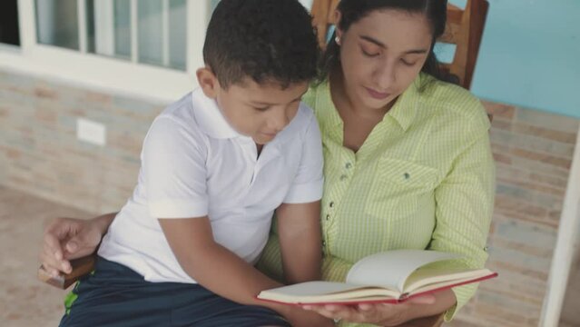 latin family, mom reading red book to her son, sitting in a rocking chair