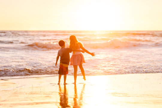Two kids together at the beach at sunset