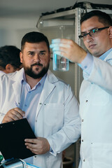 Obraz premium Young chemical technician checking liquid reagent in laboratory