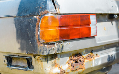 Broken car, rust on metal body, old paint. Close-up, rear view of car headlight