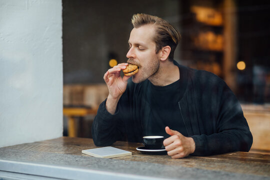 Man Eating Cookie in Cafe