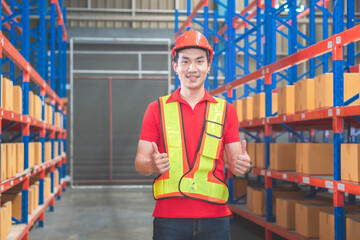 Cheerful male worker in hardhat smiling with giving thumbs up, Warehouse worker working in factory warehouse