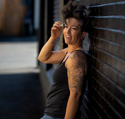 Young female energetic happy model posing with her back up against a brick wall