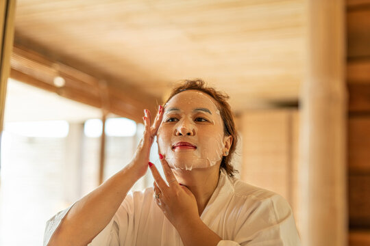 Beautiful young woman uses sheet moisturizing face mask