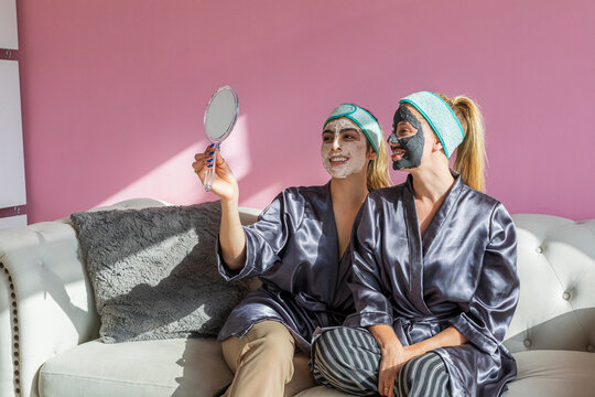 two girls with beauty masks looking at themselves in a mirror