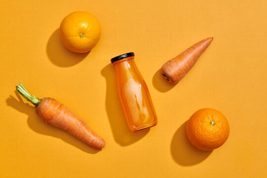 A bottle of fresh carrot smoothie, carrots and oranges on vivid yellow - Powered by Adobe