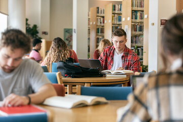 Male Student Using Laptop And Books To Study