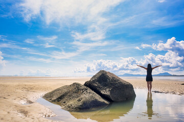 Rear view of solo woman traveler standing on a deserted beach