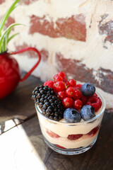 summer desserts with berries in a glass bowl and large glasses of homemade lemonade on a wooden in a cafe	
