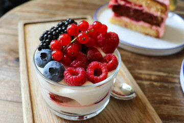 summer desserts with berries in a glass bowl and large glasses of homemade lemonade on a wooden in a cafe	