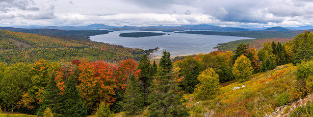 Height of Land - A panoramic overview of Mooselookmeguntic Lake and its surrounding rolling hills on a colorful but stormy Autumn day, as seen from Height of Land at side of Route 17, Maine, USA.