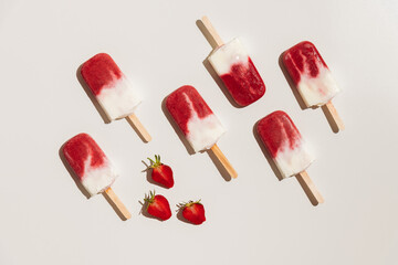 Homemade strawberry ice cream popsicles on white background