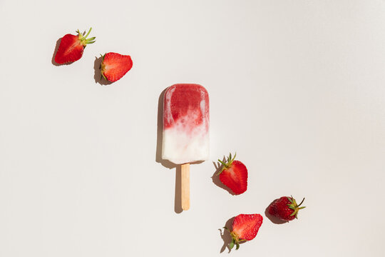 Homemade strawberry ice cream popsicles on white background