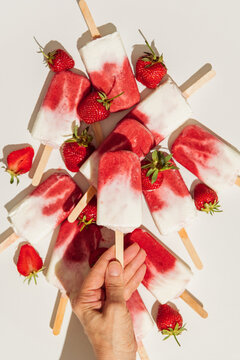 Hand holding homemade strawberry ice cream pops