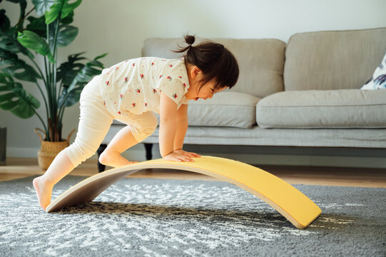 Cute girl playing with balance board  at home