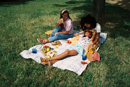 Multiethnic lesbian couple with their daughter enjoying picnic