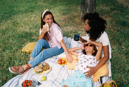 Multiethnic lesbian couple with their daughter enjoying picnic