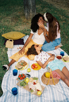 Multiethnic lesbian couple with their daughter enjoying picnic