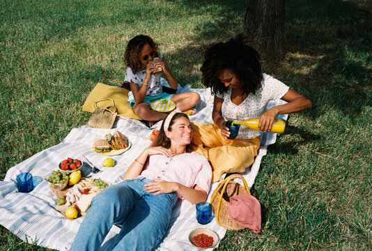 Multiethnic lesbian couple with their daughter enjoying picnic