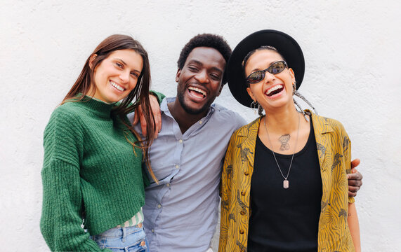 Cheerful multiracial friends standing near wall