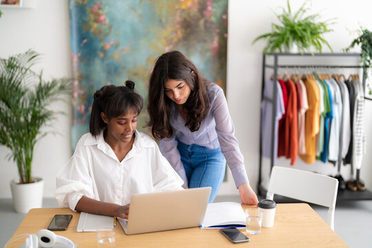 Multiracial designers working on laptop in workspace
