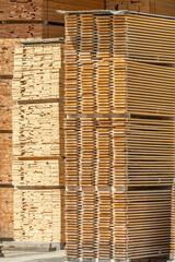 Lots of planks stacked on top of each other in the warehouse. Lumber for further use in construction. Pile of sawn boards