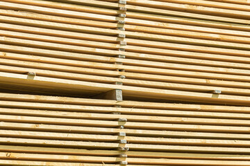 Lots of planks stacked on top of each other in the warehouse. Lumber for further use in construction. Pile of sawn boards
