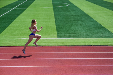 Young caucasian woman is engaged in jogging at the stadium outdoors.