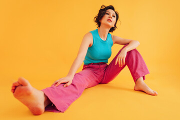 Fashionable woman sitting in vibrant studio