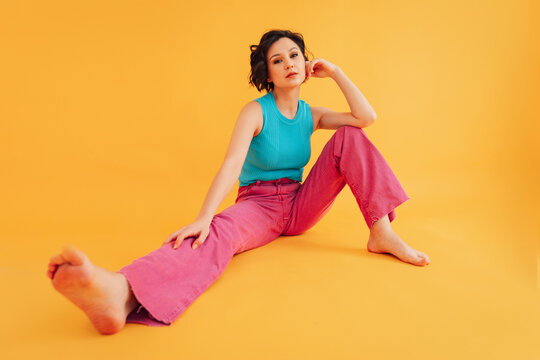 Stylish barefoot woman sitting in studio