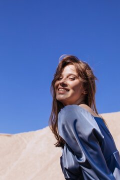 Happy woman against sky and dune
