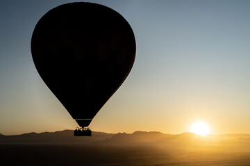 A silhouette of a hot air balloon during a sunrise 
flight in Sossusvlei, Namibia.