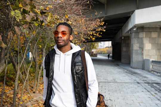 Stylish handsome black man walking by a tunnel and trees