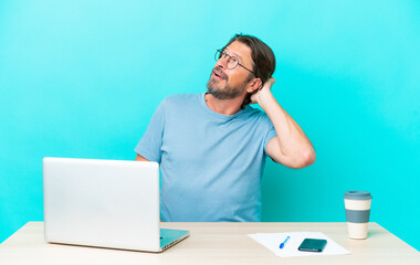 Senior dutch man in a table with a laptop isolated on blue background thinking an idea