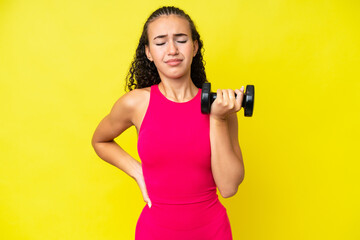 Young sport woman making weightlifting isolated on yellow background suffering from backache for having made an effort