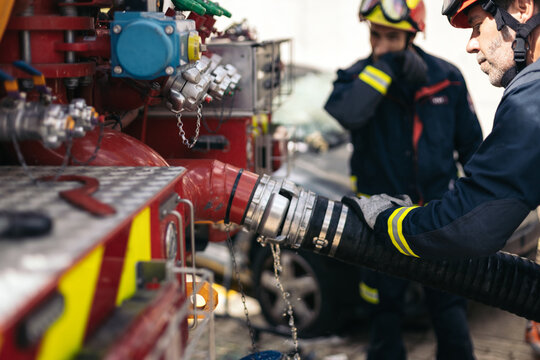 Firefighters connecting the hose to the fire truck