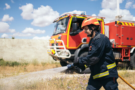 Professional firefighter using the hose to prevent a fire