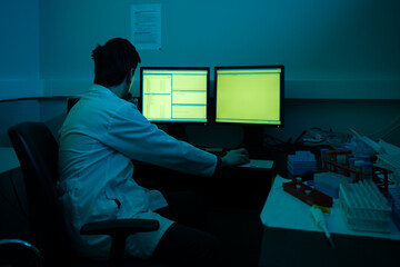 Scientist Working In A Blueish Laboratory Next To The Computer.