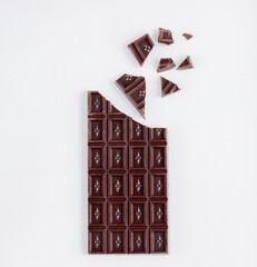 Broken chocolate bar on the white background with copy space