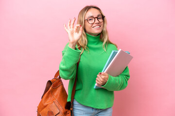 Young student woman isolated on pink background showing ok sign with fingers