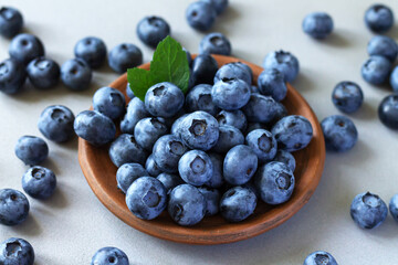 Bowl of fresh ripe blueberries with leaves on kitchen table