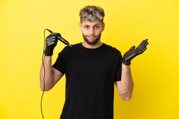 Tattoo artist caucasian man isolated on yellow background having doubts while raising hands